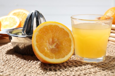 Photo of Freshly squeezed orange juice, fruits and juicer on table, closeup