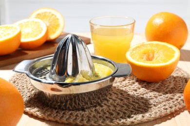 Photo of Freshly squeezed orange juice, fruits and juicer on table, closeup