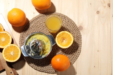 Photo of Freshly squeezed orange juice, fruits and juicer on wooden table, flat lay. Space for text