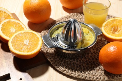 Photo of Freshly squeezed orange juice, fruits and juicer on wooden table, closeup