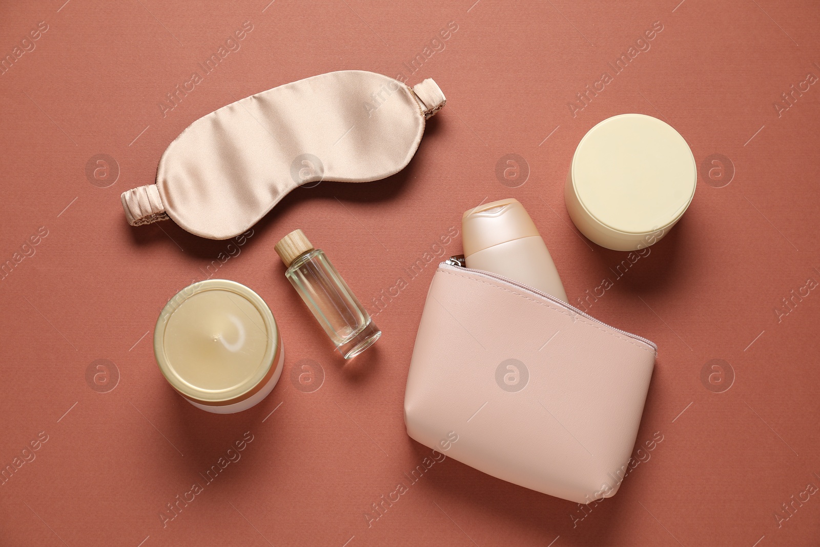 Bag with cosmetic products and sleeping mask on brown background, flat lay Photo of Bag with cosmetic products and sleeping mask on brown background, flat lay