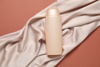 Photo of Cosmetic product and fabric on brown background, top view. Mockup for design