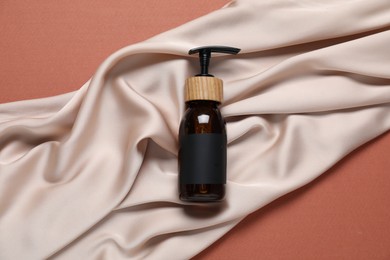 Photo of Cosmetic product and fabric on brown background, top view. Mockup for design