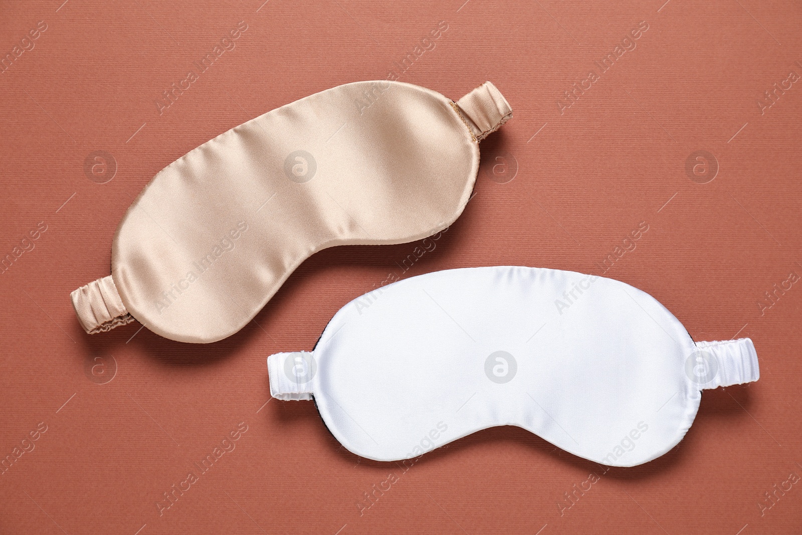 Sleeping masks on brown background, flat lay Photo of Sleeping masks on brown background, flat lay