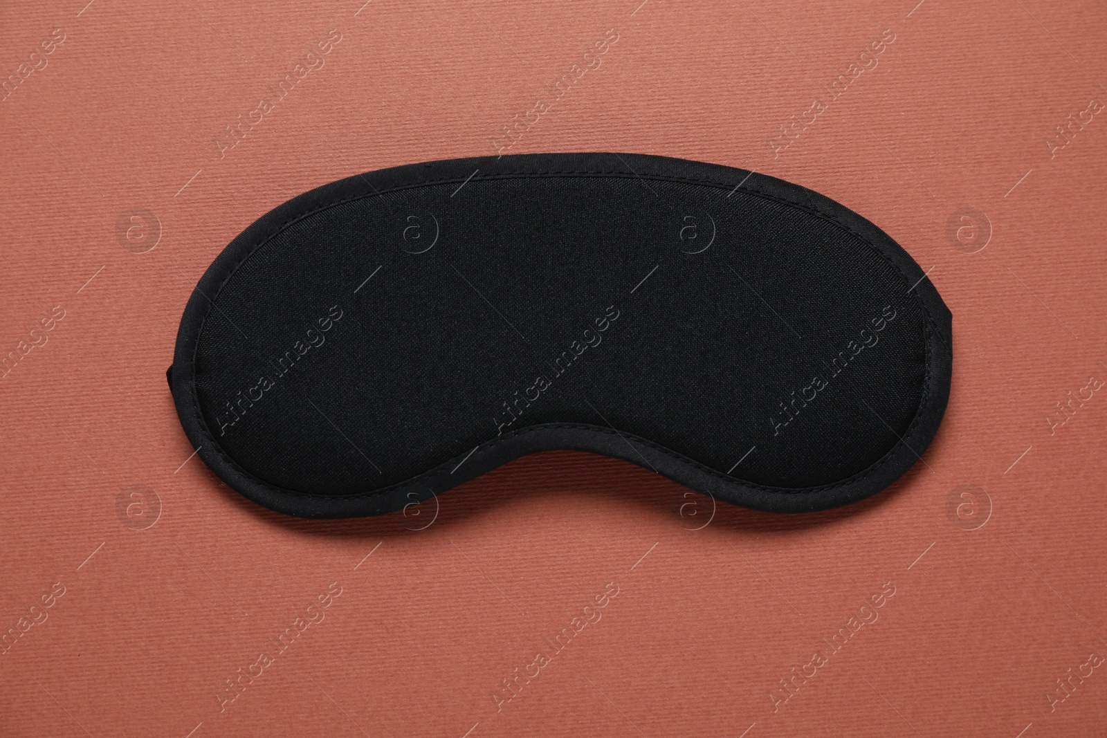 Sleeping mask on brown background, top view Photo of Sleeping mask on brown background, top view