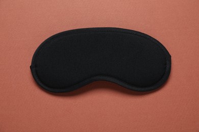Photo of Sleeping mask on brown background, top view