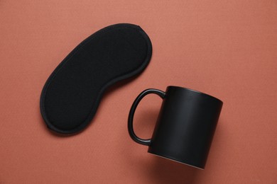 Photo of Mug and sleeping mask on brown background, flat lay. Mockup for design