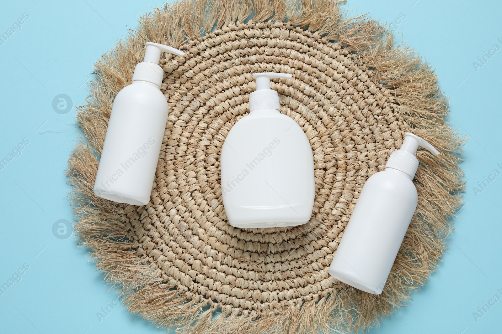 Cosmetic products and wicker mat on light blue background, flat lay. Mockup for design Photo of Cosmetic products and wicker mat on light blue background, flat lay. Mockup for design