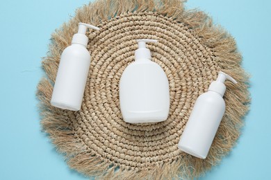 Photo of Cosmetic products and wicker mat on light blue background, flat lay. Mockup for design