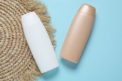 Photo of Cosmetic products and wicker mat on light blue background, flat lay. Mockup for design