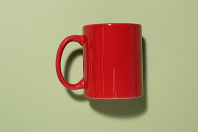 Photo of Red mug on light green background, top view. Mockup for design