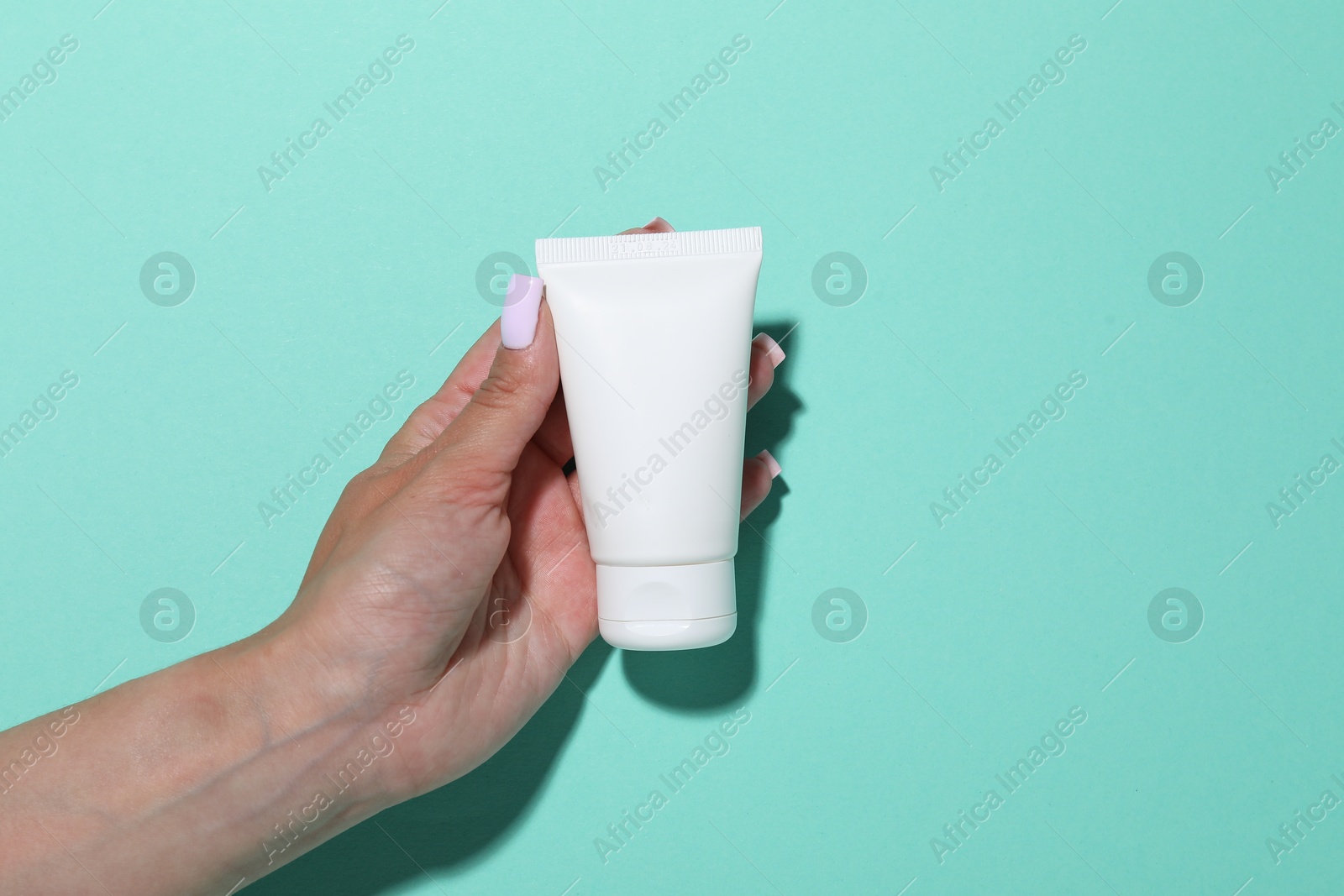 Woman with cosmetic product on turquoise background, closeup. Mockup for design Photo of Woman with cosmetic product on turquoise background, closeup. Mockup for design