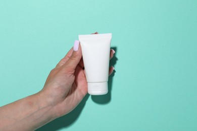 Photo of Woman with cosmetic product on turquoise background, closeup. Mockup for design