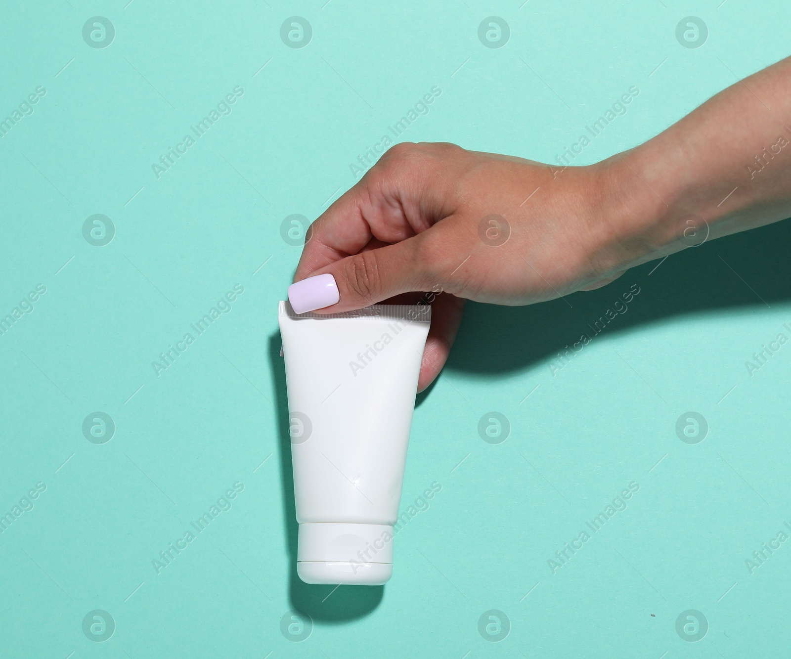 Woman with cosmetic product on turquoise background, closeup. Mockup for design Photo of Woman with cosmetic product on turquoise background, closeup. Mockup for design