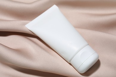 Photo of Cosmetic product on beige fabric, closeup. Mockup for design