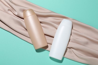 Photo of Cosmetic products and beige fabric on turquoise background, flat lay. Mockup for design