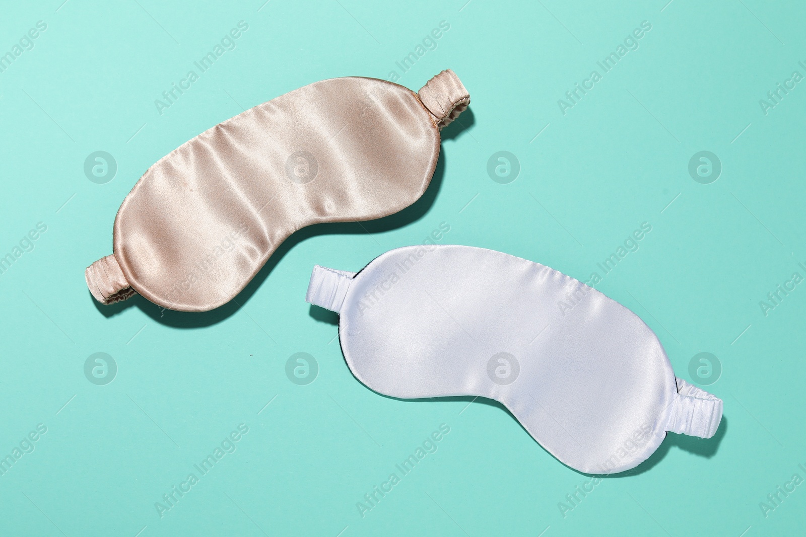 Sleeping masks on turquoise background, flat lay Photo of Sleeping masks on turquoise background, flat lay