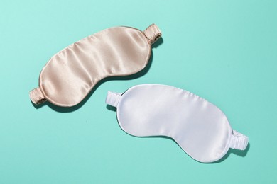 Photo of Sleeping masks on turquoise background, flat lay