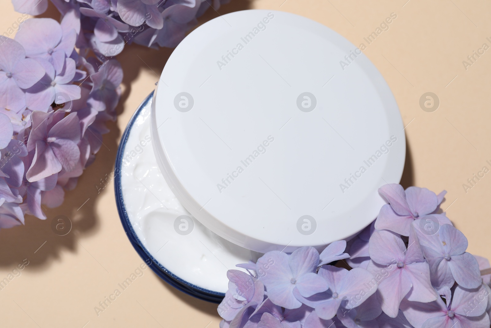 Photo of Cosmetic product and flowers on beige background, flat lay. Mockup for design