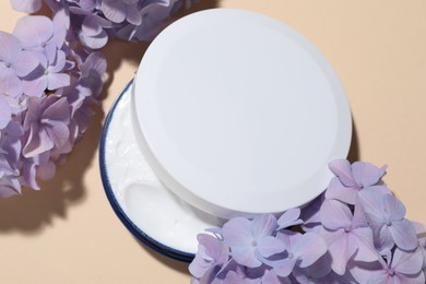 Photo of Cosmetic product and flowers on beige background, flat lay. Mockup for design
