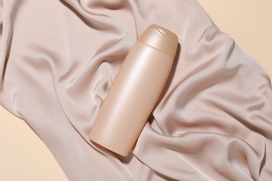 Photo of Cosmetic product and fabric on beige background, top view. Mockup for design