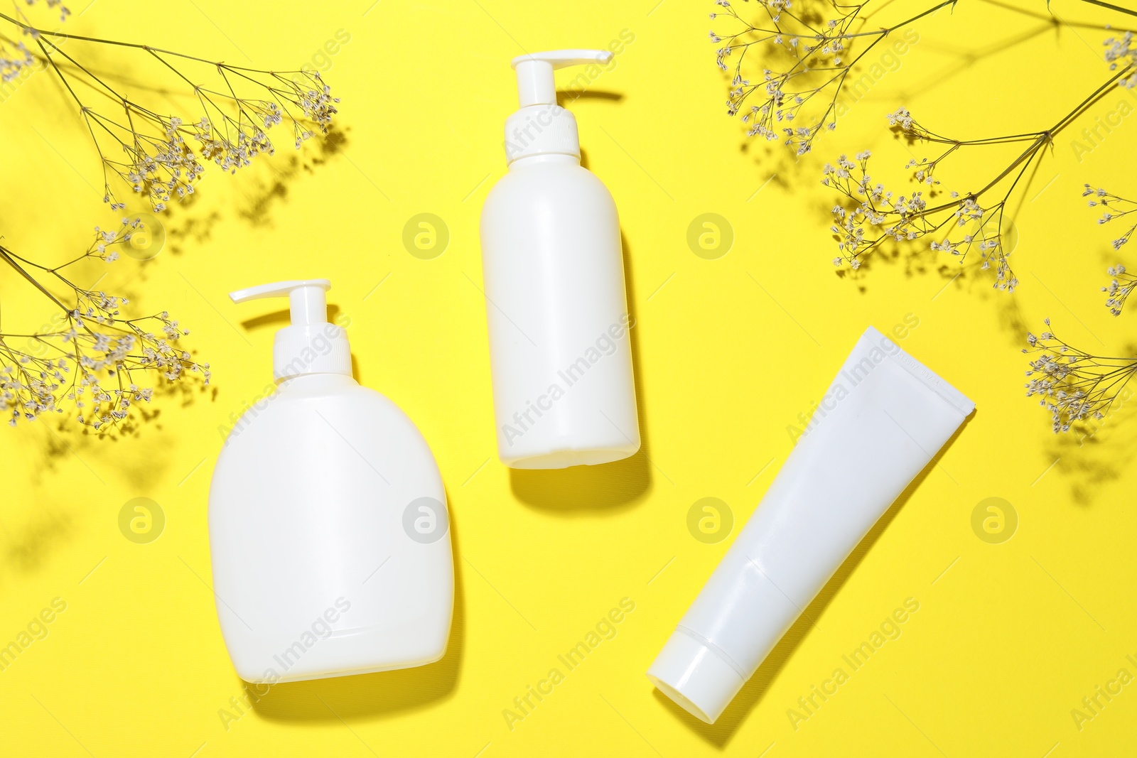 Cosmetic products and flowers on yellow background, flat lay. Mockup for design Photo of Cosmetic products and flowers on yellow background, flat lay. Mockup for design