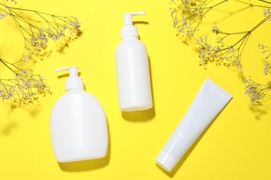 Photo of Cosmetic products and flowers on yellow background, flat lay. Mockup for design