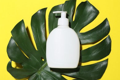 Photo of Cosmetic product and leaf on yellow background, top view. Mockup for design