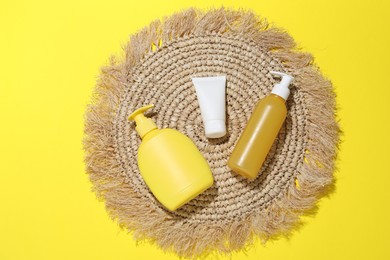 Photo of Cosmetic products and wicker mat on yellow background, flat lay. Mockup for design