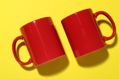 Photo of Red mugs on yellow background, top view. Mockup for design