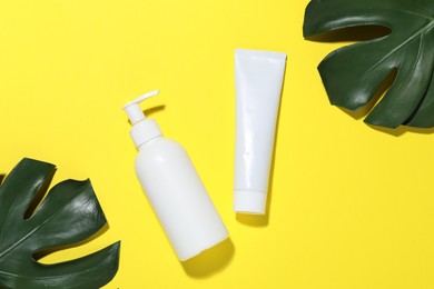 Photo of Cosmetic products and leaves on yellow background, flat lay. Mockup for design