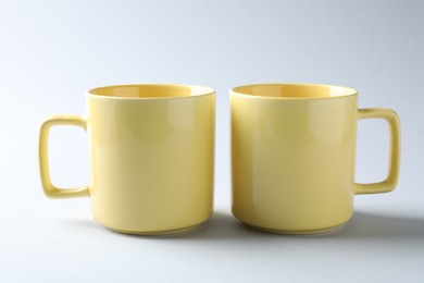 Photo of Yellow mugs on light background. Mockup for design