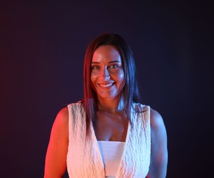 Photo of Portrait of smiling woman in neon lights against dark background