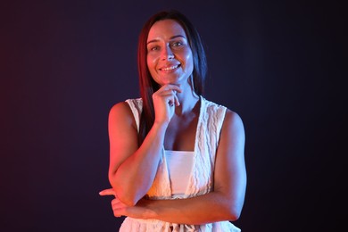 Photo of Portrait of smiling woman in neon lights against dark background