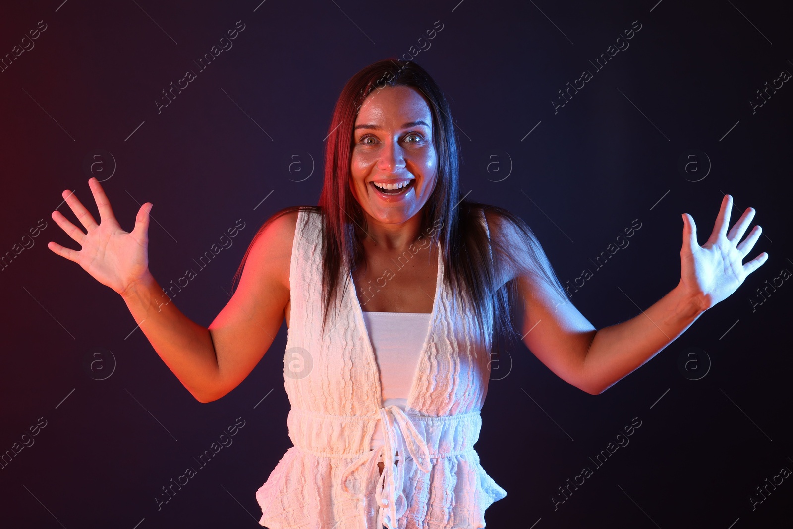 Portrait of smiling woman in neon lights against dark background Photo of Portrait of smiling woman in neon lights against dark background