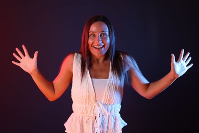 Photo of Portrait of smiling woman in neon lights against dark background