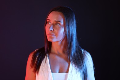 Photo of Attractive woman in neon lights against dark background