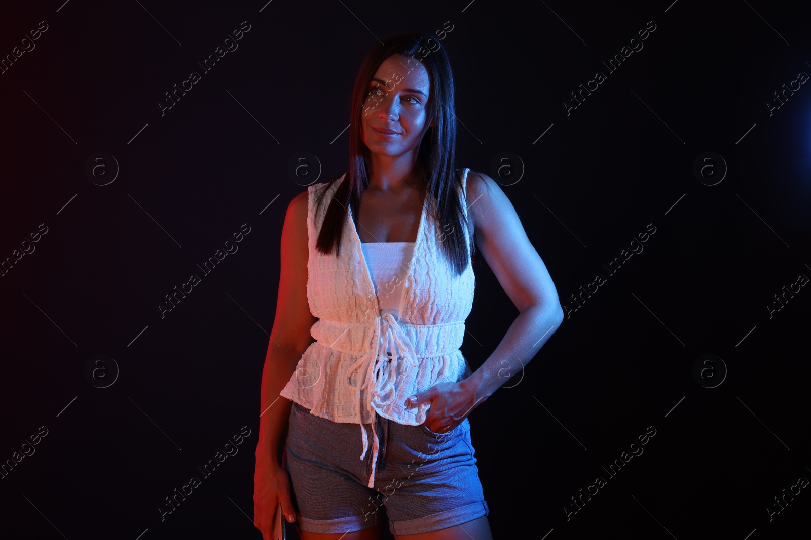 Attractive woman in neon lights against black background Photo of Attractive woman in neon lights against black background