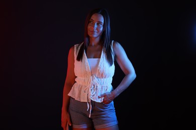 Photo of Attractive woman in neon lights against black background