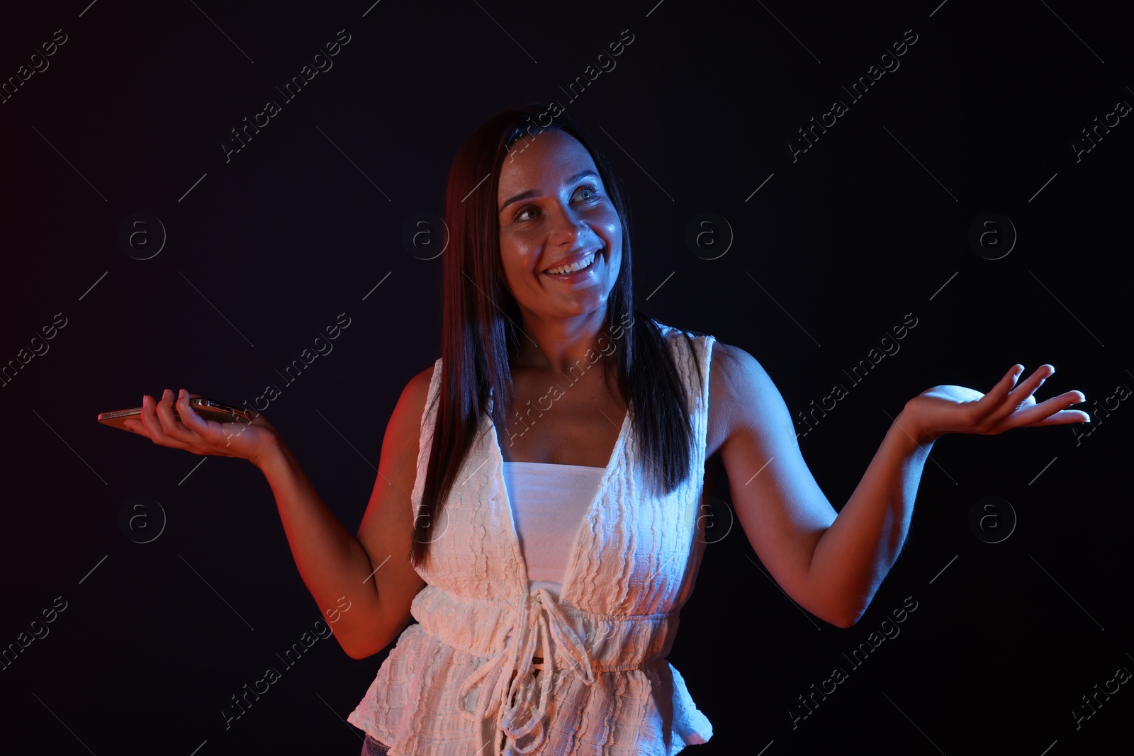 Portrait of smiling woman in neon lights against dark background Photo of Portrait of smiling woman in neon lights against dark background