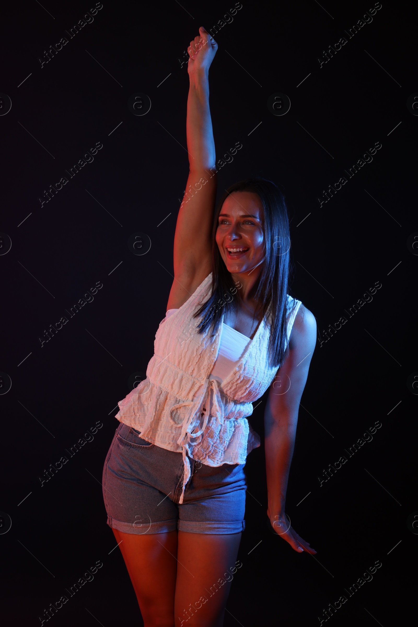 Happy woman in neon lights against black background Photo of Happy woman in neon lights against black background