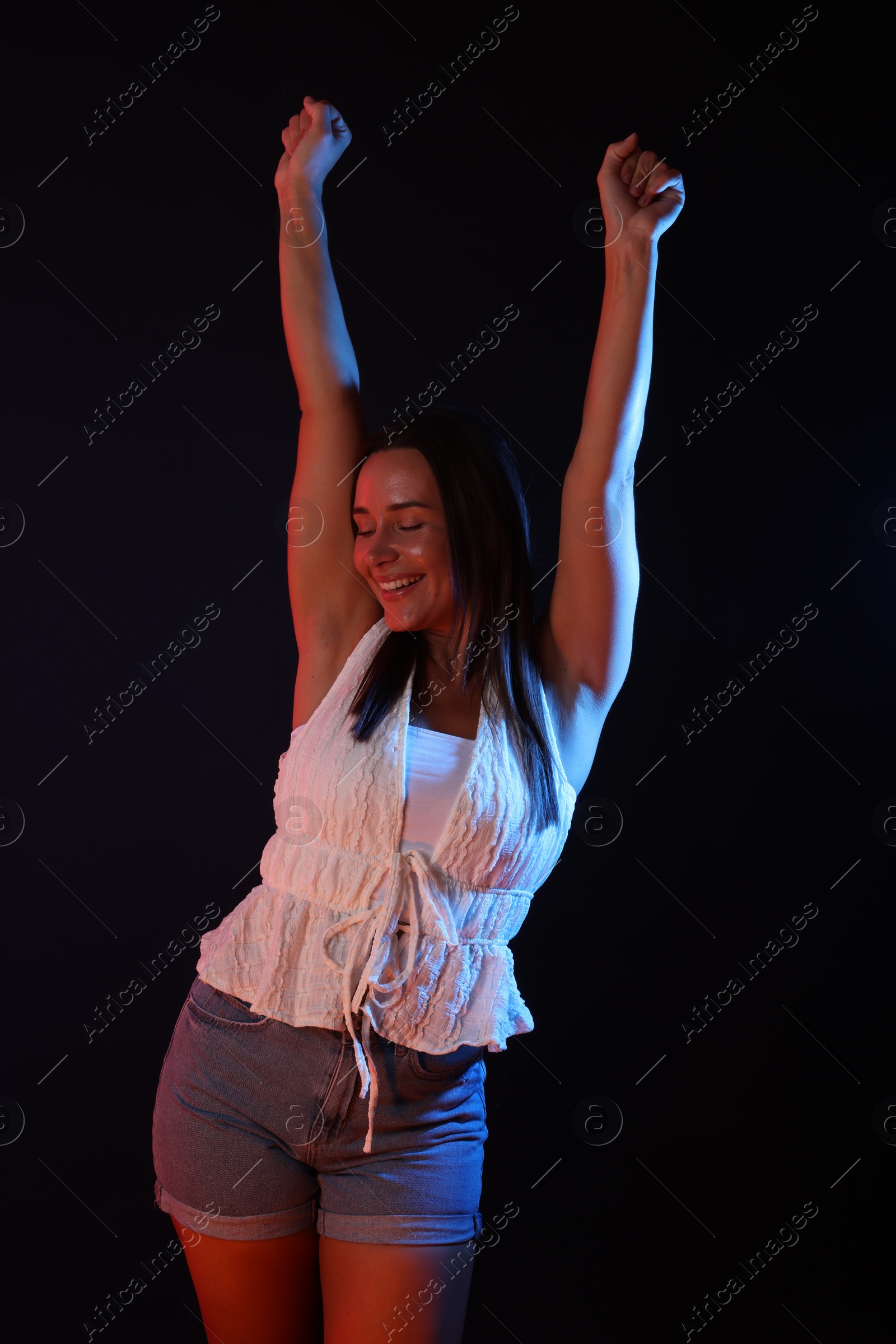Happy woman in neon lights against black background Photo of Happy woman in neon lights against black background