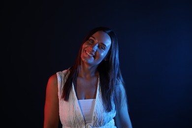 Photo of Portrait of smiling woman in neon lights against black background