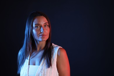 Photo of Beautiful woman in neon lights against black background. Space for text