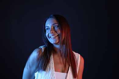 Photo of Smiling woman in neon lights against black background