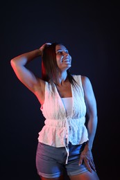 Photo of Smiling woman in neon lights against black background