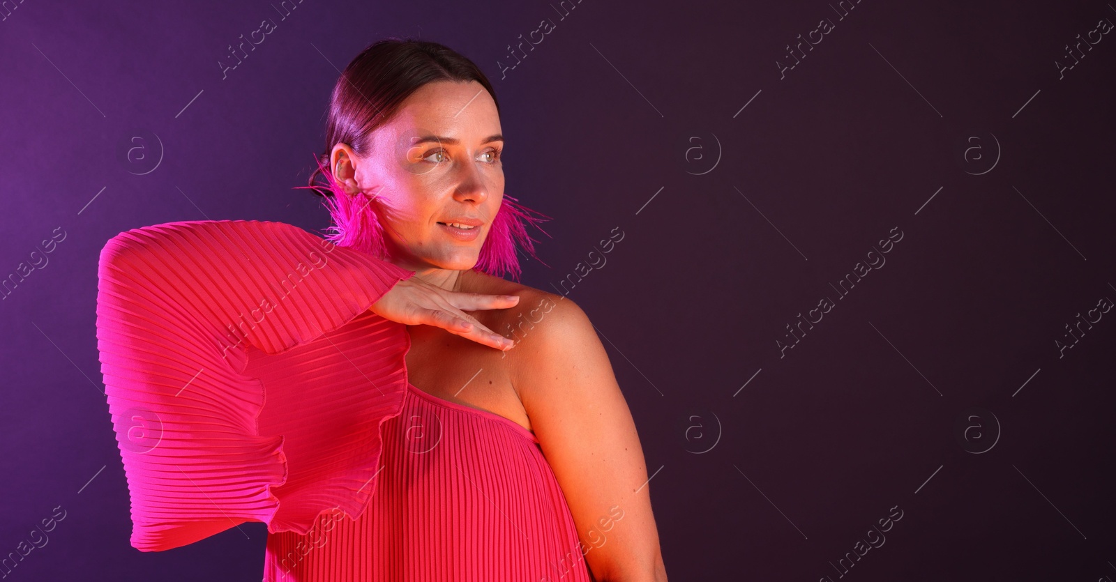 Beautiful woman wearing fur earrings in neon lights against purple background. Space for text Photo of Beautiful woman wearing fur earrings in neon lights against purple background. Space for text