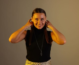 Photo of Smiling woman in neon lights against grey background