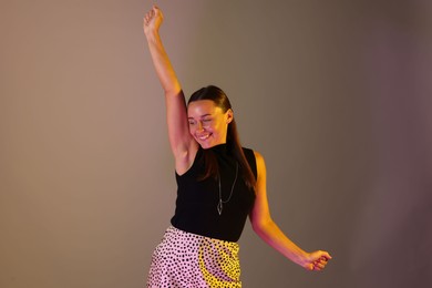 Photo of Smiling woman in neon lights against grey background