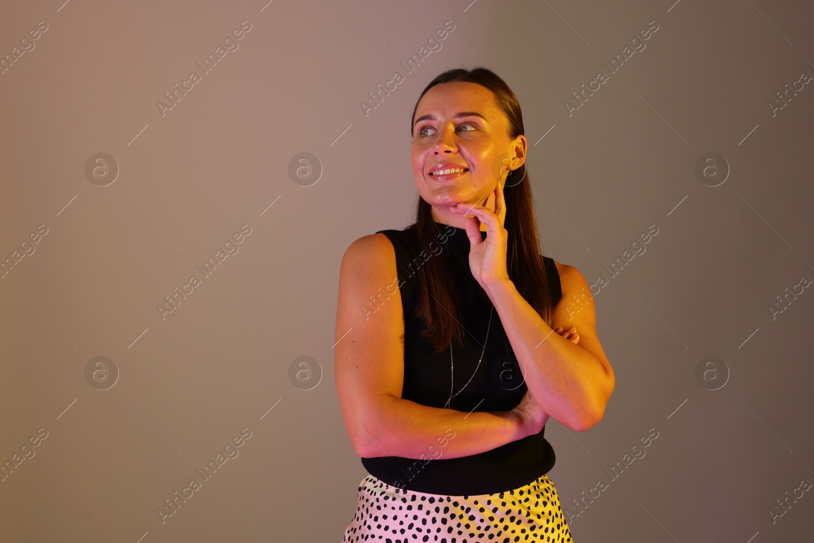 Smiling woman in neon lights against grey background. Space for text Photo of Smiling woman in neon lights against grey background. Space for text